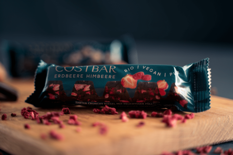 Bio vegane Schokoladenriegel mit Erdbeeren und Himbeeren auf einem Holzbrett