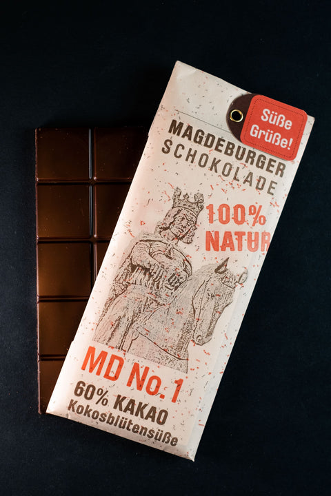 Bio vegane Schokolade mit 60% Kakaoanteil Magdeburger Schokolade mit dunklem Hintergrund mit offener Schokoladentafel im Hintergrund
